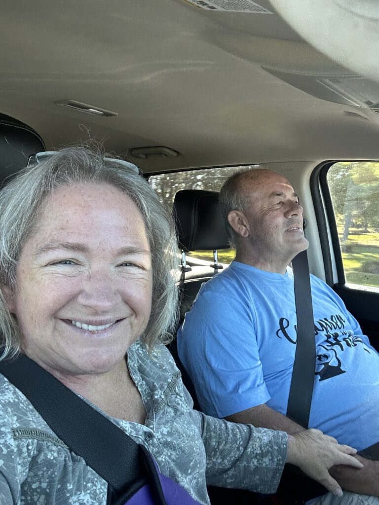 Amy & Ken in the truck, seat belts on and smiling as they travel.