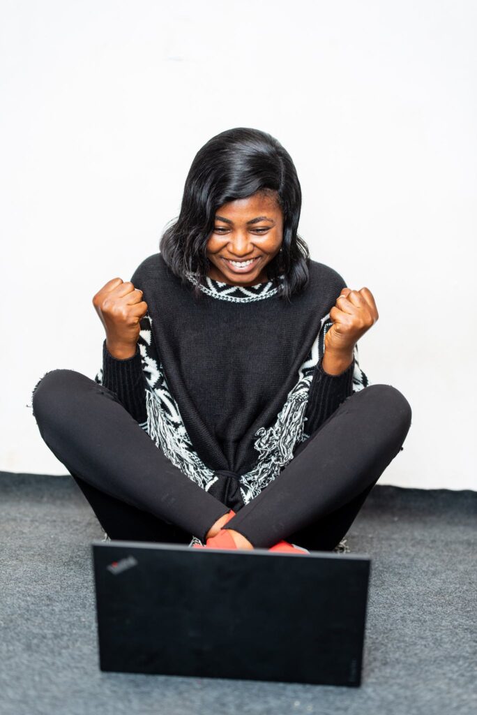 Excited black woman showing yes gesture near laptop